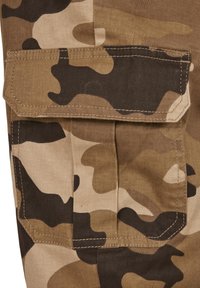Close-up of a brown and black camouflage fabric cargo pocket with a flap and visible stitching.