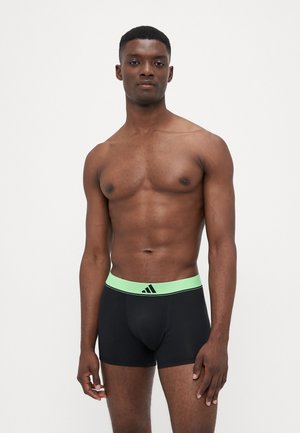 Schwarze Boxershorts aus glattem, elastischem Material, mit einem hell-limettengrünen Bund und schwarzem Adidas-Logo.