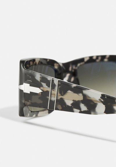 Ochelari de soare tortoiseshell negri și gri, cu un cadru gros, lentile degradé și accente argintii pe templu. Design plat cu un finisaj lucios.