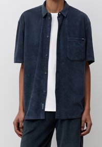 Kortärmad skjorta i mörkblå frottétyg, med knappstängning fram, en bröstficka och en avslappnad passform.
