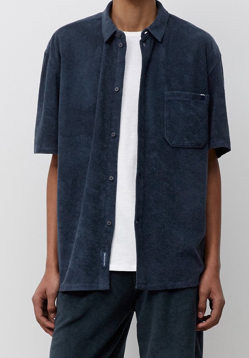 Kortärmad skjorta i mörkblå frottétyg, med knappstängning fram, en bröstficka och en avslappnad passform.