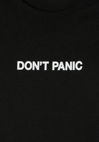 T-shirt in cotone nero con stampa di testo bianca che recita "NON ENTRA PANICO." Collo rotondo, texture liscia, design semplice.