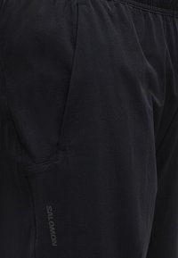 Κοντινό πλάνο από μαύρα αθλητικά σορτς Salomon που δείχνει πλαϊνή τσέπη και ελαστική μέση.