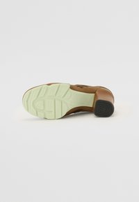 Brown leather shoe with a textured surface, a chunky heel, and a light green rubber sole featuring a patterned tread design.