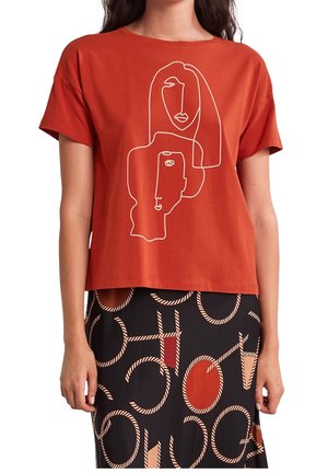 Haut à manches courtes couleur rouille avec un dessin en ligne continue blanche représentant deux visages abstraits, associé à une jupe noire ornée de motifs circulaires beiges et rouges.