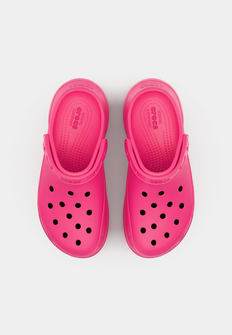 Rosa Gummischuhe mit runder Form, die mehrere große Löcher und ein strukturiertes Muster auf dem Fußbett aufweisen. Bequeme Ausführung mit Rückenriemen.