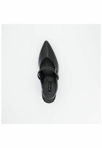 Chaussure en cuir noir avec un bout pointu, une bride de cheville et un détail de boucle. Texture lisse avec un design à côté ouvert. Étiquette intérieure visible.
