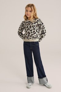 Pleteni pulover v bež in črnem leopardjem vzorcu, okrogla izreza; kombiniran z širokimi temno modrimi kavbojkami z kontrastnimi manšetami.