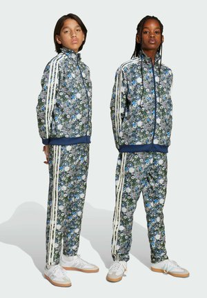 Blommönstrade joggingdräkter i blått, grönt och vitt, med zippered jackor med hög krage och vita sidosträck på byxorna.