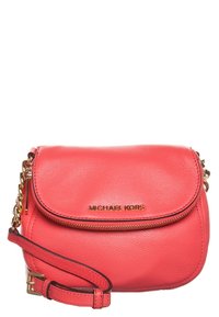 Korálově růžová kožená crossbody taška Michael Kors se zlatým řetízkem, přední zipovou kapsou a logem na klopě.
