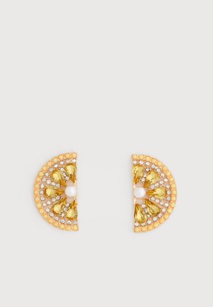 Gyldne halvcirkelformede øreringe med gule dråbeformede sten, små klare krystaller og hvide perler i midten på en hvid baggrund.