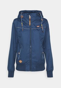 Marinblå lättviktsjacka med dragkedja, justerbar huva och elastiska ärmslut; har beige detaljer och en logotyp på framsidan.