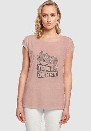 Hellrosa T-Shirt mit hochgeschlagenen Ärmeln, das eine Graustufenillustration von Tom und Jerry sowie den fetten Text "TOM UND JERRY" am unteren Rand zeigt.