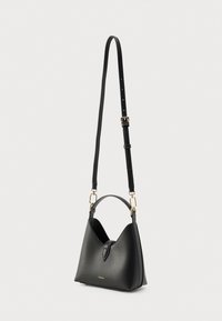 Čierna kožená kabelka s výrazným dizajnom v tvare písmena V, obsahujúca krátku rukoväť, nastaviteľný popruh a zlaté kovové doplnky.