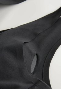 Crne kupaće gaće s elegantnim dizajnom, izrađene od rastezljivog materijala, s izrezima i glatkim teksturama na površini.