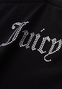 Μαύρο ύφασμα με θαυμαστές ρουμπίνες που σχηματίζουν τη λέξη "Juicy" σε καλλιγραφική γραμματοσειρά, αναδεικνύοντας μια λείο υφή και λαμπερούς τόνους.