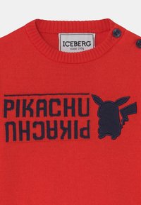 Rød sweater med ribbet halsudskæring, der har marineblå broderet tekst "PIKACHU" og en Pikachu silhuet. To marineblå knapper ved kraven.