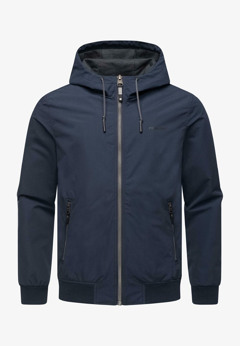 Marinblå zip-up jacka med huva, tillverkad av slätt tyg. Har två sidofickor med dragkedja och elastiska mudd för en säker passform.