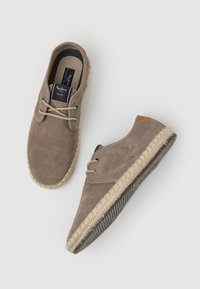 Zapatos de ante marrón con cordones y suela de yute trenzado, con una textura suave y un acento de cuero marrón claro en el talón.