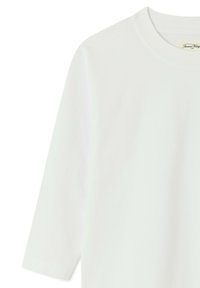 Chemise blanche à manches longues avec col rond et une petite étiquette en tissu au niveau du col indiquant "American Vintage".