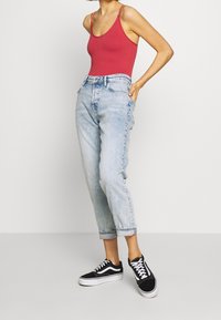 Röd räfflad bodysuit, ljusblå avslappnade jeans med cropped längd och svarta sneakers med vita snörningar. Enkelt och avslappnat outfit.