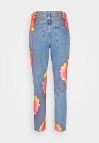 Fatos de ganga em azul claro com um corte descontraído, apresentando grandes padrões florais coloridos em rosa, amarelo e laranja nas laterais e nos bolsos.