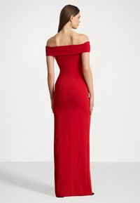 Raudona su peties iškirpte sukurta suknelė, siaura siluetu, iki žemės ilgio dizainas, matomi siūlų detalės ir lygus paviršius.