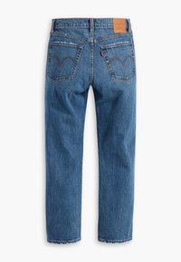 Jean en denim bleu, taille haute, coupe droite, avec deux poches arrière, coutures signature, une petite étiquette rouge et un patch de marque en cuir marron.
