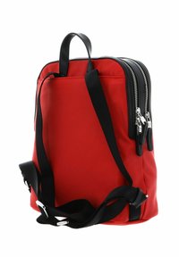 Sac à dos rouge en nylon avec des bretelles noires et des accents de fermeture éclair, présentant une forme rectangulaire élégante et deux fermetures éclair latérales pour un accès facile.