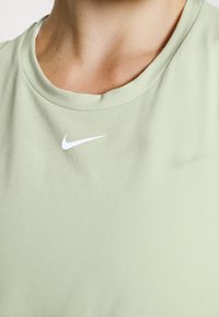 Vaaleanvihreä puuvillainen t-paita, jossa on pyöreä kaula-aukko ja pieni valkoinen Nike-logo rinnassa. Sileä pinta, lyhyet hihat.