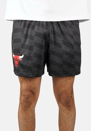 Schwarze Sportshorts mit wiederholtem "Chicago" Schriftmuster und einem roten Chicago Bulls-Logo am linken Oberschenkel, getragen von einer Person.
