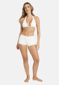 Biały bikini z prążkowanego materiału, składające się z topu na szyję z trójkątnymi miseczkami oraz pasujących, wysokowciętych szortów. Gładka tkanina o dopasowanym kroju.