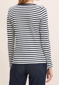 Kousek s dlouhým rukávem, pruhovaný v námořnické modré a bílé barvě, vyrobený z jemné bavlny. Má kulatý výstřih a slim fit, s úzkými pruhy střídajících se v barvě.