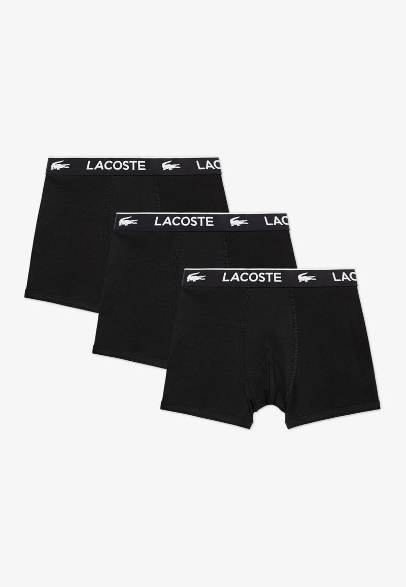 Čierne bavlnené boxerky v sade po troch kusoch, s potlačeným bielym logom Lacoste na kontrastnom páse v páse. Hladká textúra, dĺžka do polovice stehen.