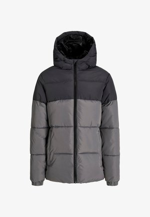 Must ja hall turskejakk kapuutsiga, millel on tikitud sektsioonid, kombineeritud musta särgi, mustade dressipükste ja hallide spordijalatsitega.