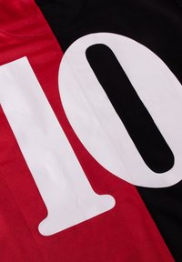 Rode en zwarte sporttrui met een groot wit nummer "10" op de voorkant, gemaakt van glad synthetisch materiaal met zichtbare stikdetails.
