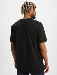 Black cotton t-shirt with short sleeves, a crew neck, and a relaxed fit. The fabric appears smooth and soft to the touch.