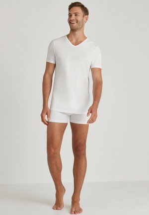 White short-sleeve V-neck shirt and matching boxer shorts made of soft fabric. Simple design with a smooth texture and tailored fit.