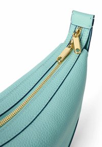 Una borsa in pelle turchese con una superficie testurizzata, caratterizzata da una cerniera dorata con doppi cursori e un bordo blu a contrasto.