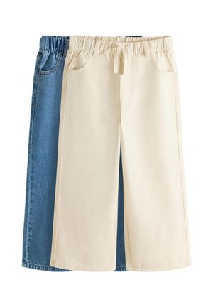 Zwei Paare weit geschnittener Hosen, eines beige mit Kordelzugbund vorne und eines aus blauem Denim hinten, beide mit Vordertaschen.
