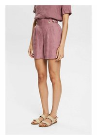 Shorts taille haute mauve en tissu léger avec boutons décoratifs, plis et poches latérales. Associés à des sandales plates beige.