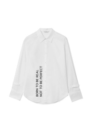 Camicia bianca a maniche lunghe con colletto classico, chiusura con bottoni e design testuale lungo il lato: "NATO PER ESSERE REALE, NON PER ESSERE PERFETTO."