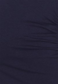 Tecido azul marinho com uma textura suave, apresentando rugas subtis por toda a parte, indicando um material macio e elástico.