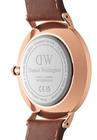 Stainless steel watch back with a rose gold finish and engraved details. Brown leather strap with white stitching. Serial number visible.
