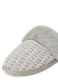 Zapatilla de tela trenzada gris con un acento de pelo gris esponjoso en la parte superior. La suela es plana y está hecha de un material suave.