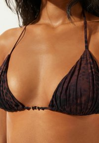 Trojúhelníkový horní díl bikin v tmavě hnědé barvě s jemným leopardím vzorem. Má tenká ramínka a uzlový středový spoj se zlatým akcentem. Měkká textura.