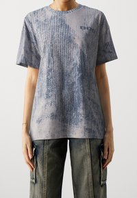 Šedé tričko s texturovaným vzorem v odstínech modré, kulatým výstřihem, krátkými rukávy a potiskem na přední straně.