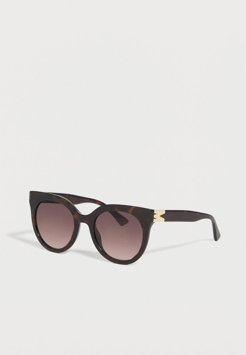 Cat-eye tortoiseshell sunglasses with gradient brown lenses and gold "M" detail on temples, shown angled on white background.