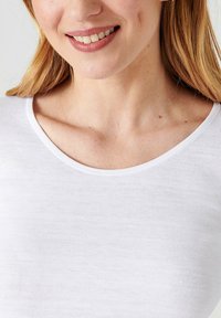 Witte geribde top met korte mouwen en een brede ronde hals, zachte textuur en gladde stiksels. Subtiele huidskleur zichtbaar bij de hals. 