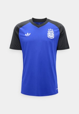 Niebieska koszulka piłkarska z czarnymi rękawami, logo Adidas po prawej stronie klatki piersiowej oraz emblemat Argentynskiego Związku Piłkarskiego po lewej stronie klatki piersiowej.